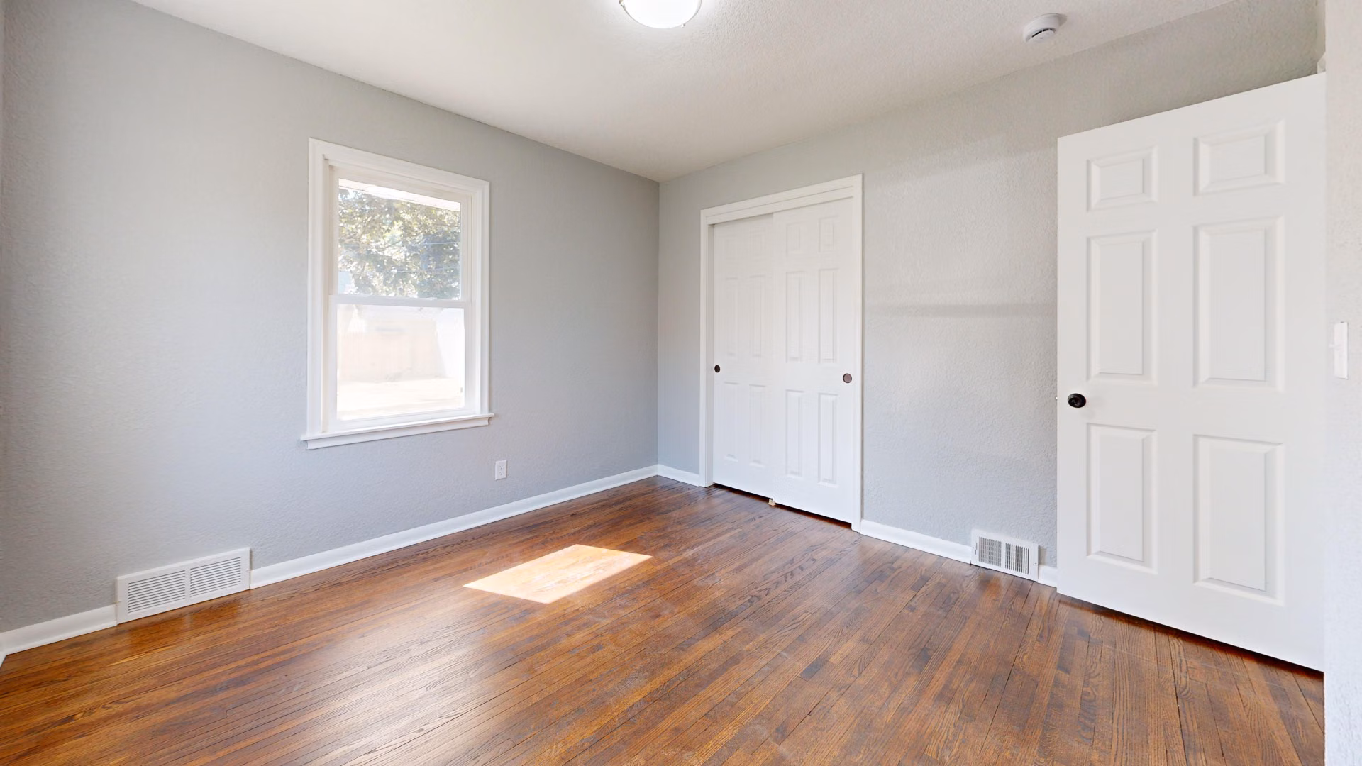 Freshly repainted room with warm white walls and refinished wood floors