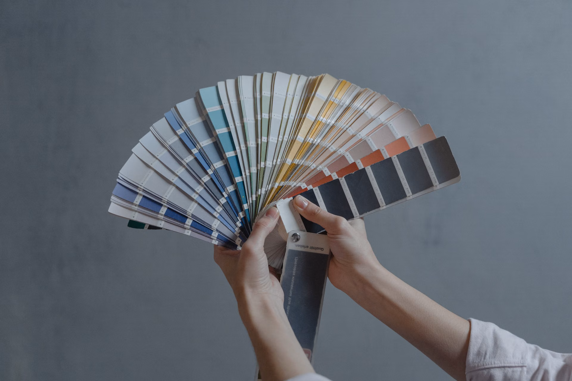 Hands fanning out a deck of paint color swatches