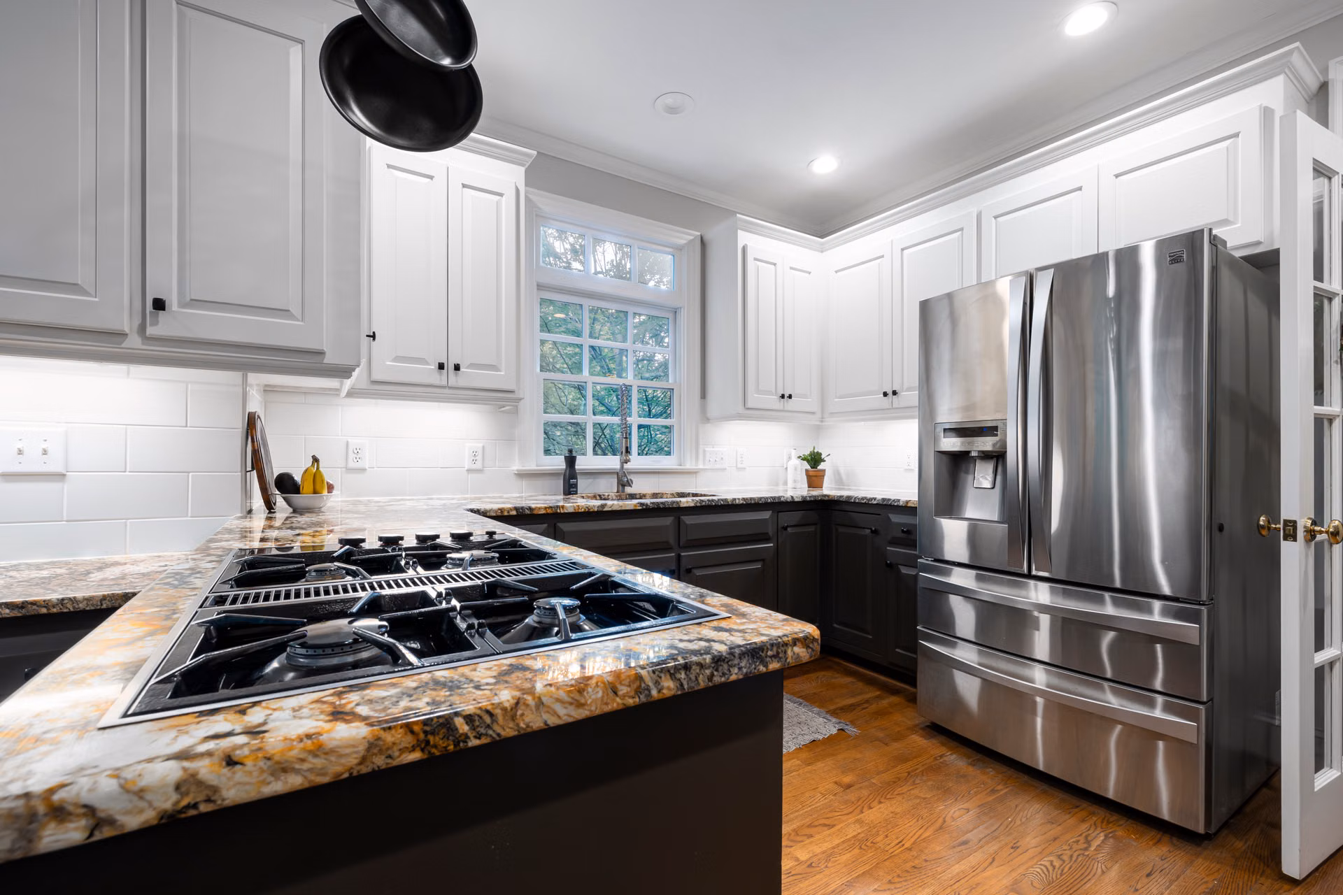 Kitchen with white painted upper cabinets and a dark two-tone island