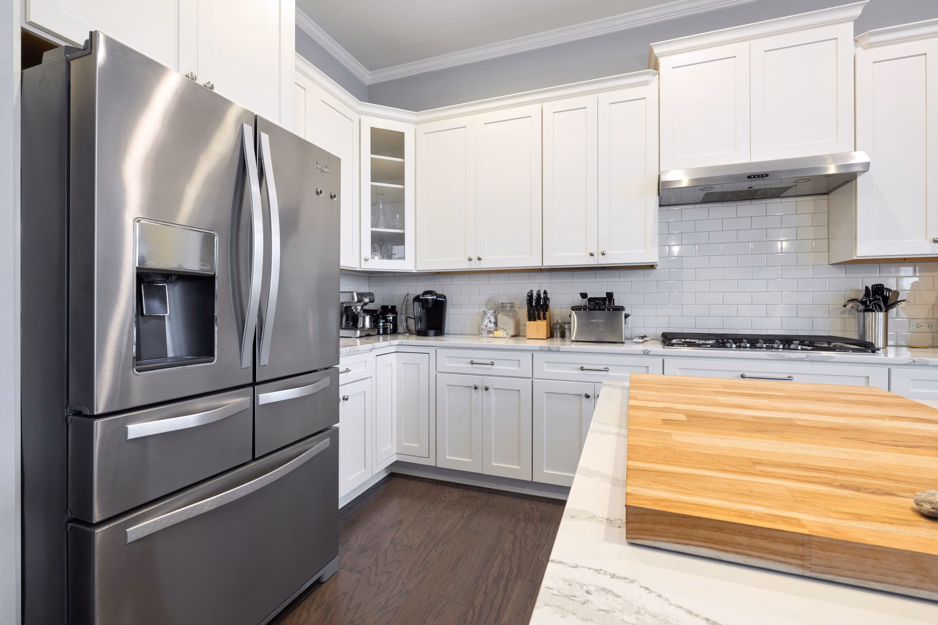 Kitchen with white cabinets, subway tile, and a butcher block island