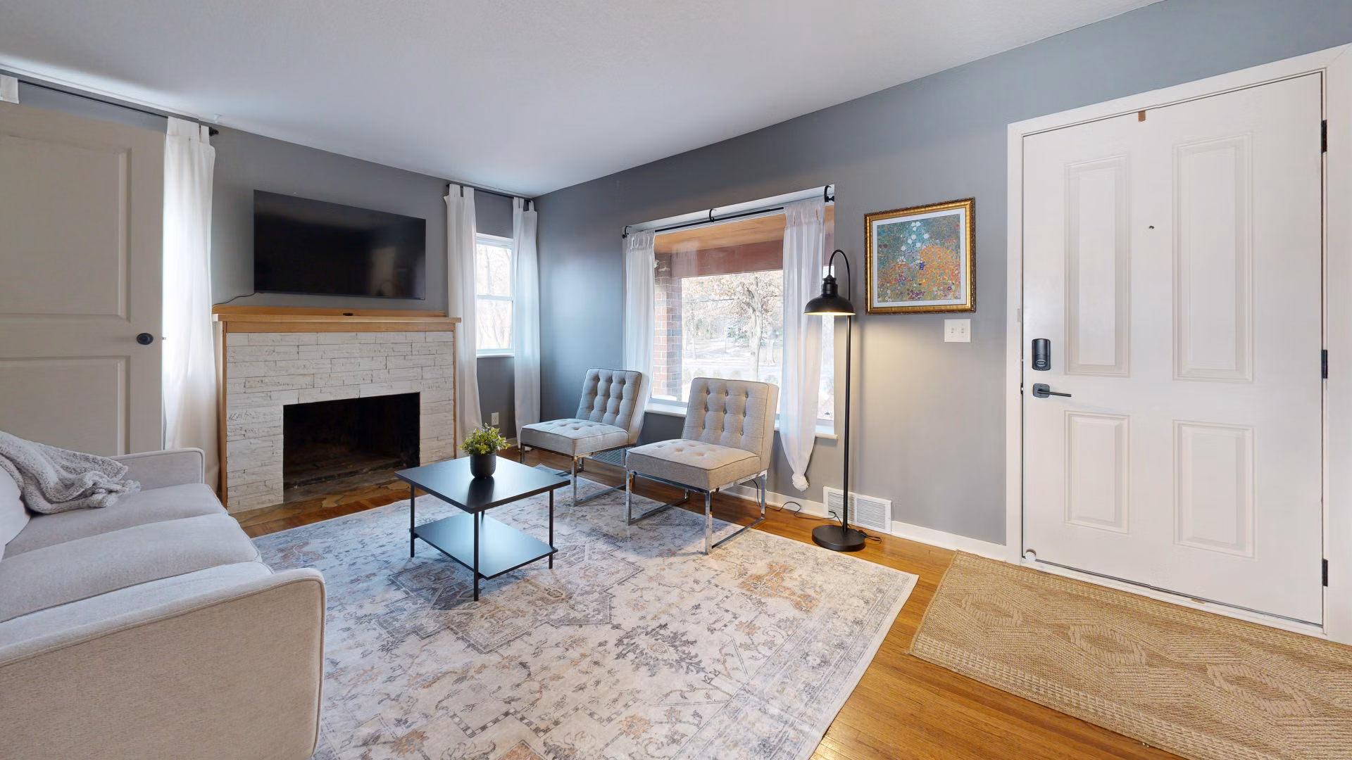Living room with soft gray walls, white trim, and a painted brick fireplace