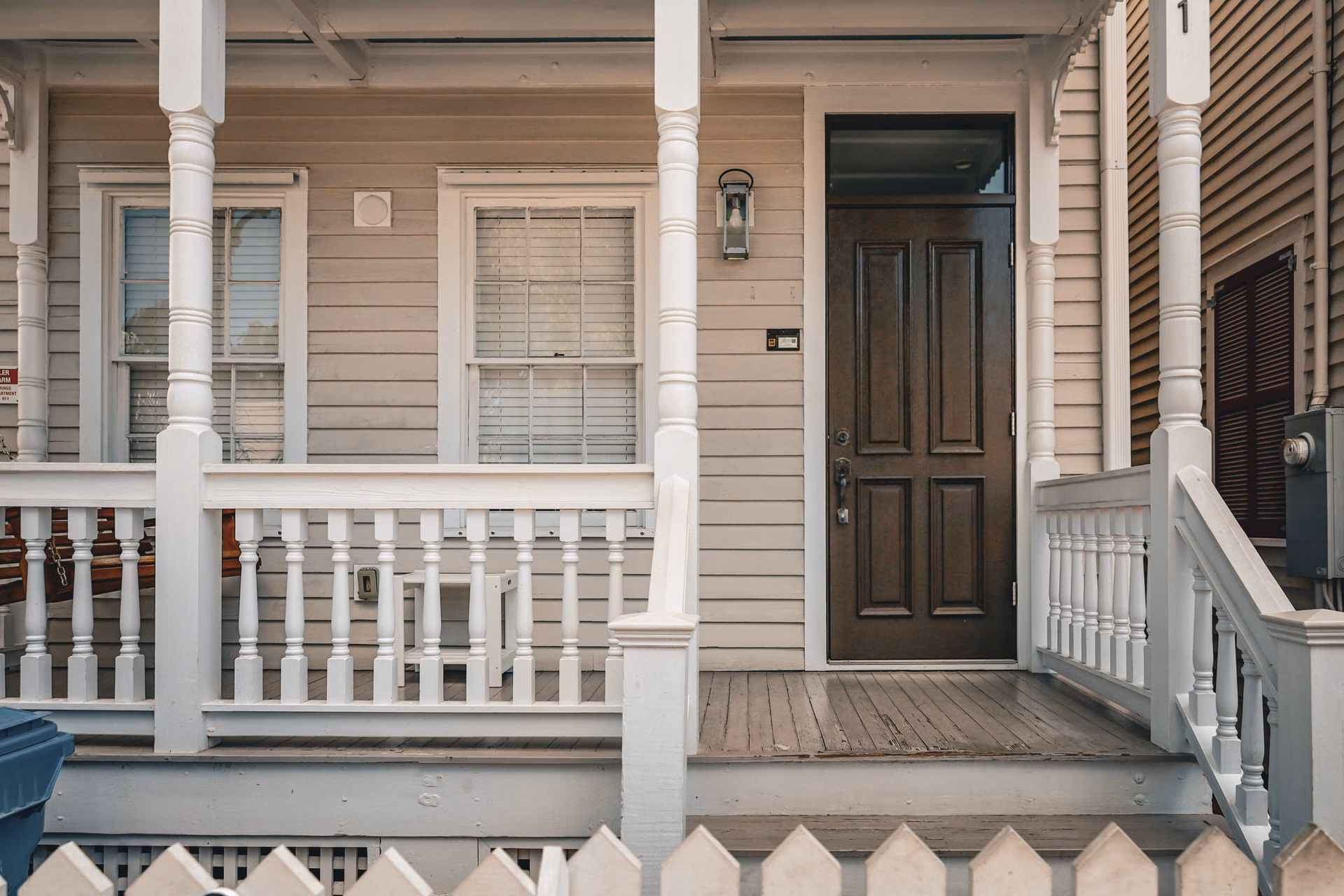 Front porch with freshly painted siding, railings, and a dark stained door